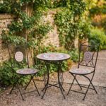 Conjunto de jardín compuesto por mesa redonda y dos sillas plegables de estructura metálica negra con asiento y tablero de mosaico decorativo, ideal para terraza o patio exterior.