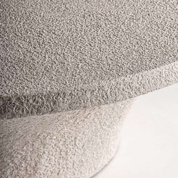 Primer plano del borde y textura de la mesa de centro Sion en cemento beige.