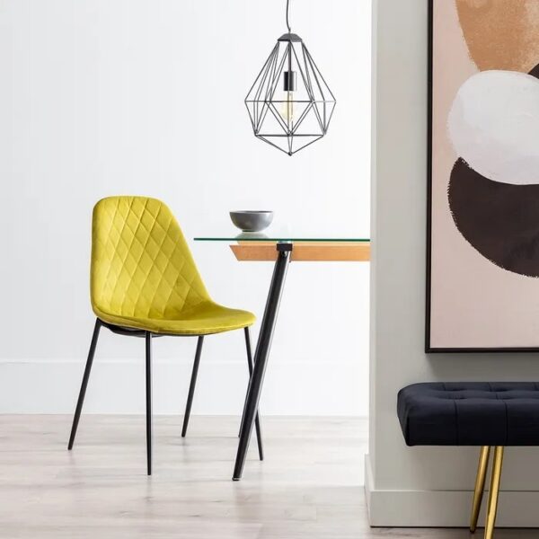 Silla verde en un comedor moderno con mesa de madera y lámpara colgante