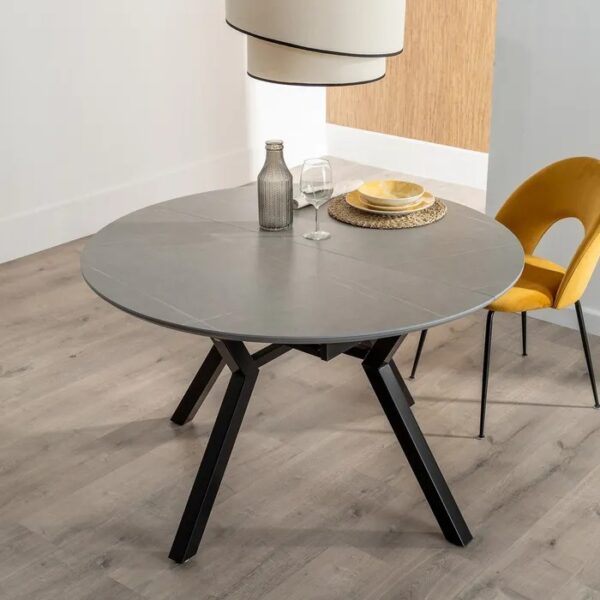 Mesa extensible gris-negro en un ambiente decorado con sillas y lámpara.