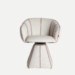 Sillón giratorio modelo Siena de la marca Kodu, con tapizado en tono beige y costuras decorativas en rojo, diseño contemporáneo y base acolchada.