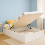 Base abatible lateral blanca abierta en dormitorio juvenil con pared azul pastel, escritorio de madera clara y luz natural