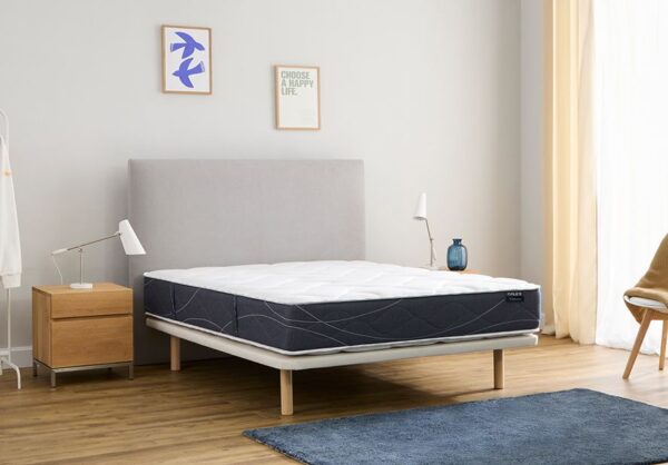 Somier Flex Tapiflex tapizado gris claro con colchón Habana, cabecero gris, mesita de madera y lámparas blancas en un dormitorio luminoso