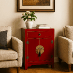 Mesita roja con herrajes dorados en un salón de inspiración asiática, entre sofá y sillón beige