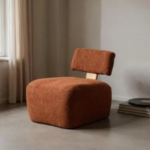Sillón moderno tapizado en tejido color terracota con respaldo bajo y base amplia.