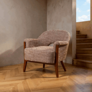 Sillón tapizado beige-marrón con estructura de madera sobre suelo de parquet y fondo neutro