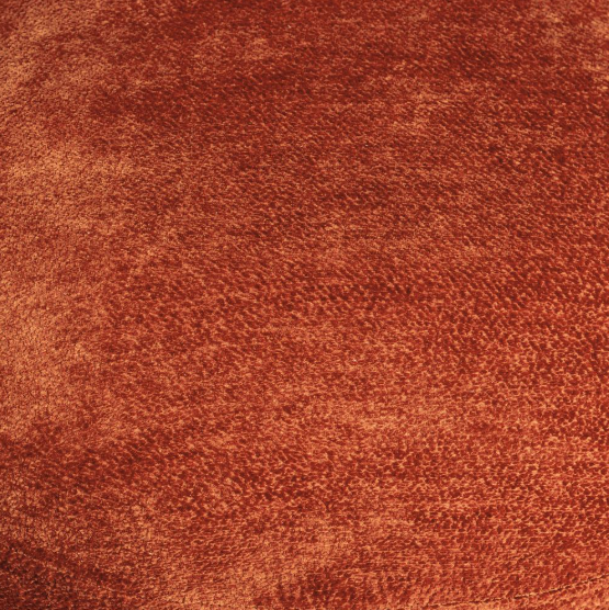 Sillón moderno tapizado en tejido color terracota con respaldo bajo y base amplia.