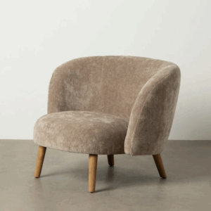 Sillón tapizado color taupe con estructura curva y patas de madera sobre suelo gris