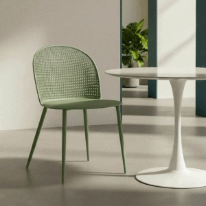 Silla verde de polipropileno con patas metálicas junto a mesa blanca en ambiente interior luminoso