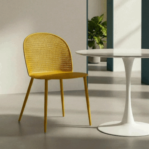 Silla color amarillo fabricada en polipropileno con respaldo calado y patas metálicas sobre fondo blanco