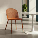 Silla color teja de polipropileno con patas metálicas junto a mesa blanca en ambiente interior moderno