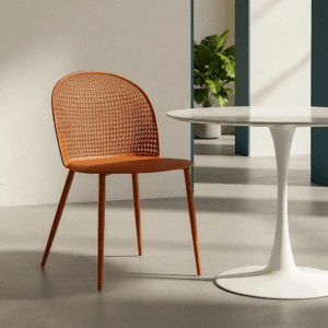 Silla color teja de polipropileno con patas metálicas junto a mesa blanca en ambiente interior moderno