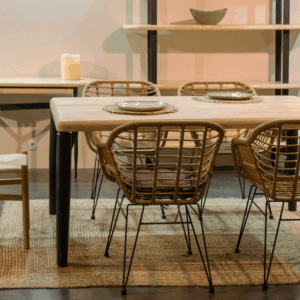 Mesa de comedor Moon en madera de roble con sillas de ratán sobre alfombra natural.