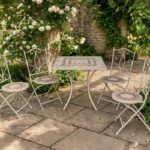 Conjunto de jardín compuesto por mesa redonda y dos sillas plegables de estructura metálica negra con asiento y tablero de mosaico decorativo, ideal para terraza o patio exterior.